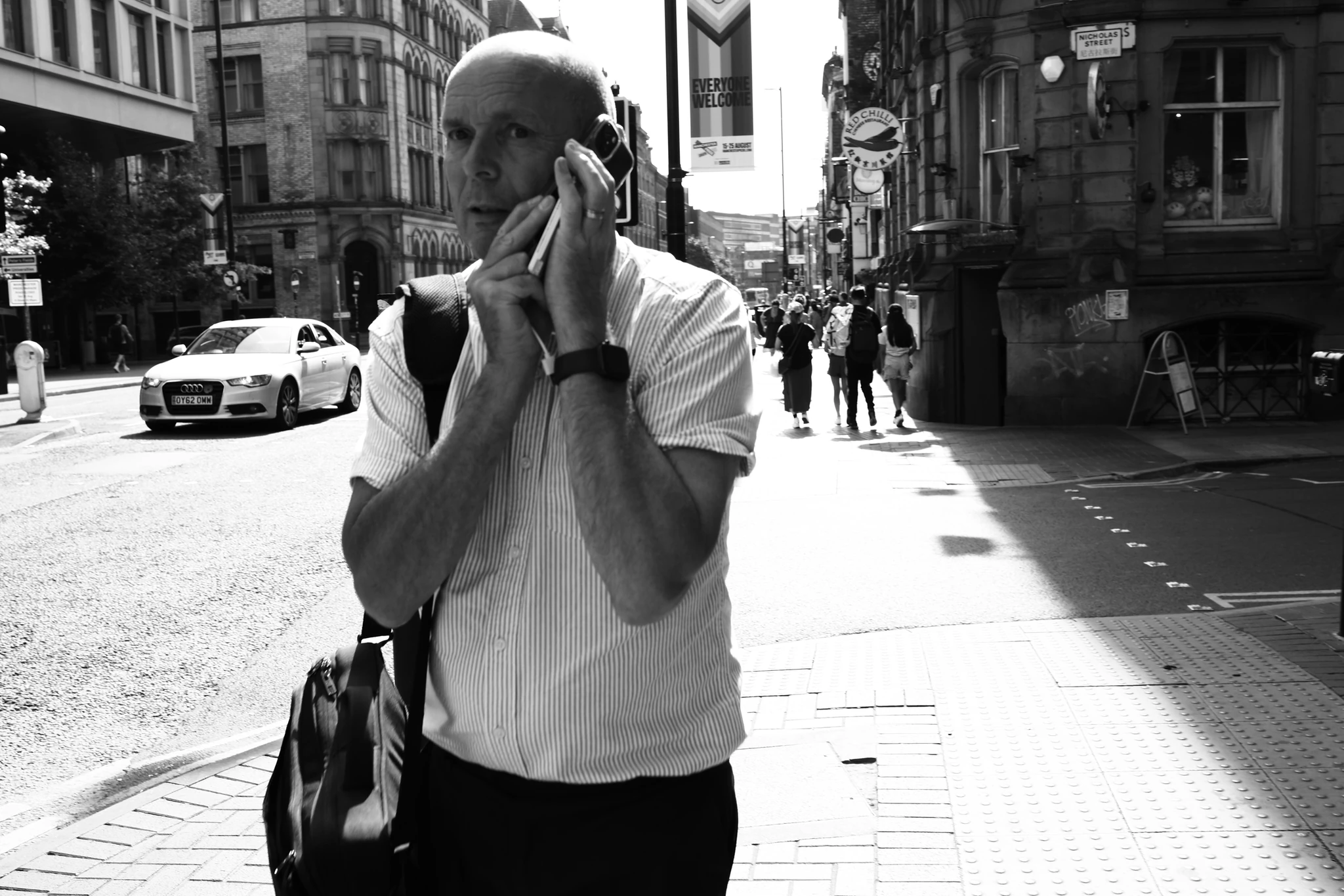 A black-and-white portrait of a person using a phone on a city street