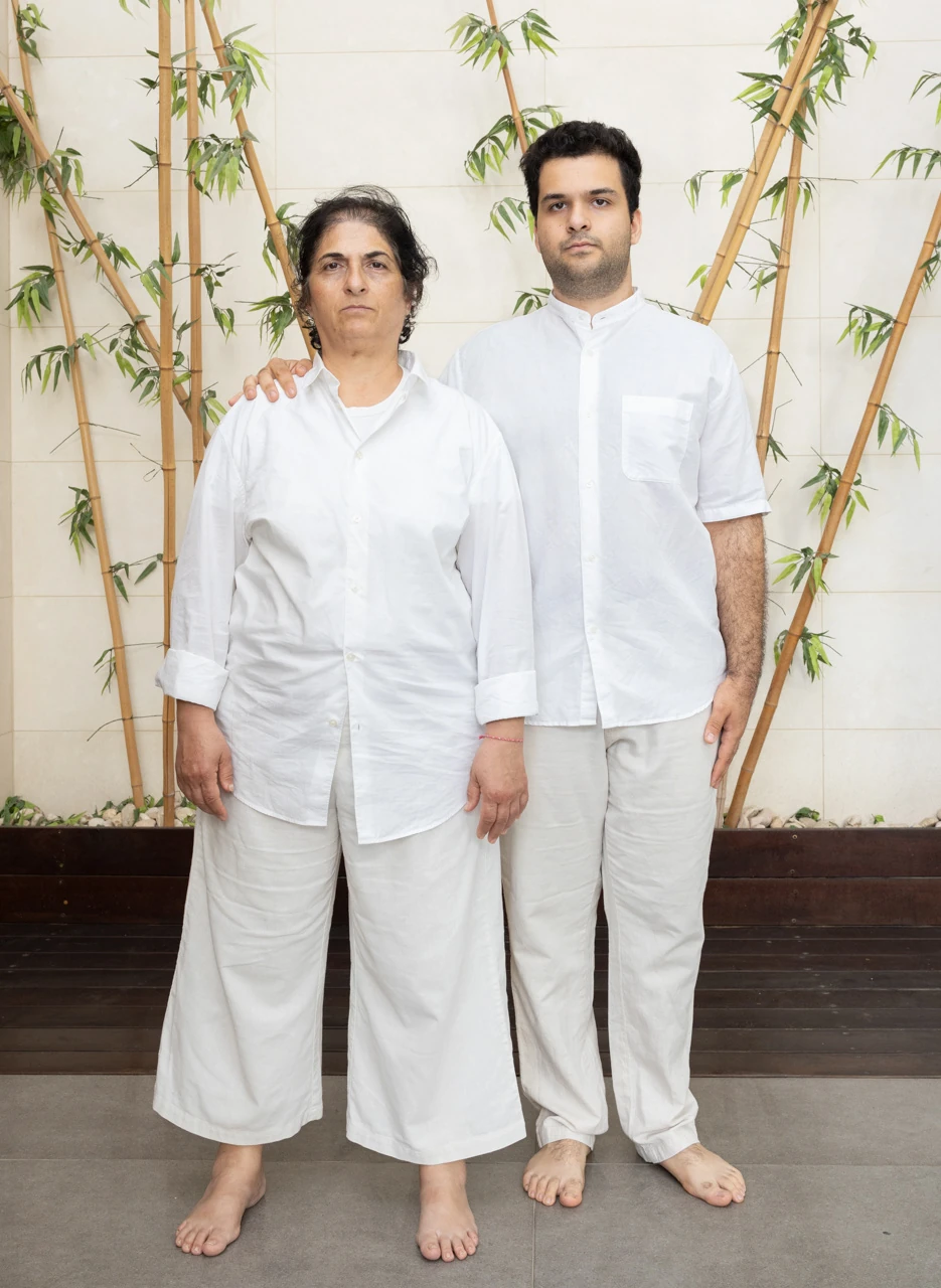 Two people dressed in white standing beneath plants